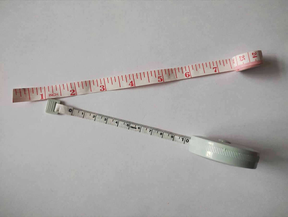 Two soft tailor's tape measures, one marked in inches and one in centimeters, lying on a white surface