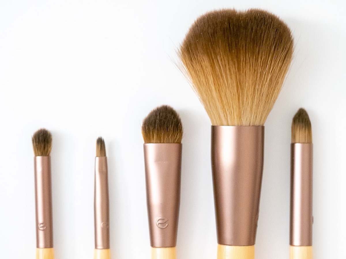 Five makeup brushes with bamboo handles and rose-gold ferrules, from a large fluffy face brush to small tapered brushes